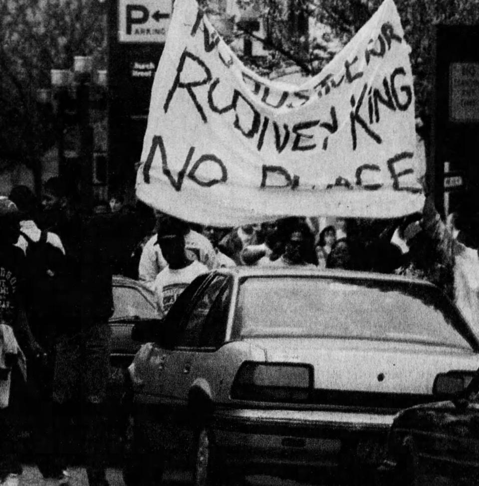 Demonstrators from the Rutgers University area carry a banner over a car stopped on George Street in New Brunswick on Friday, May 1, 1992.