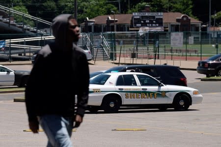 A young man walks in front of a police patrol parked in front of a high school a day after violent clashes between police and protesters broke out on streets overnight in Memphis