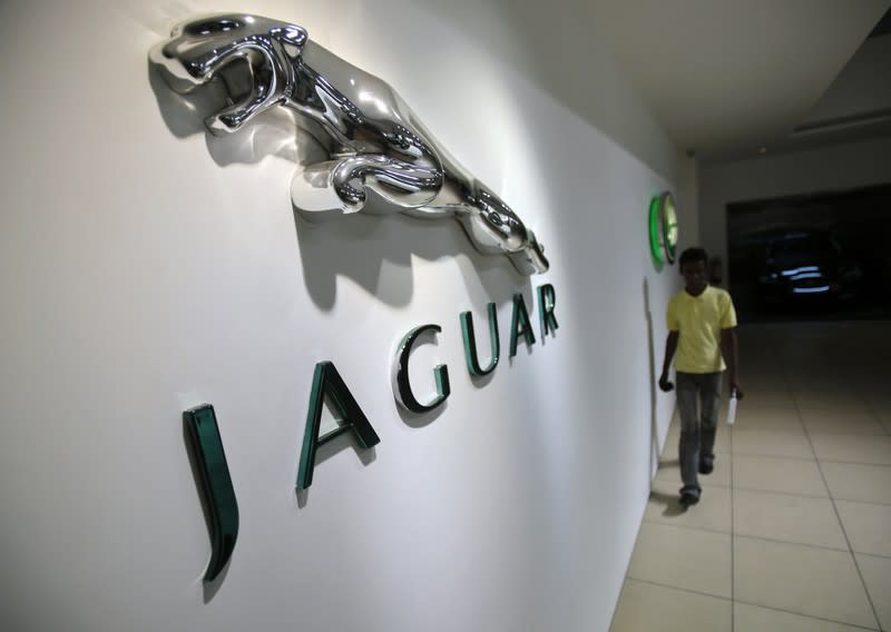 A showroom attendant walks past company logos at a Jaguar Land Rover showroom in Mumbai