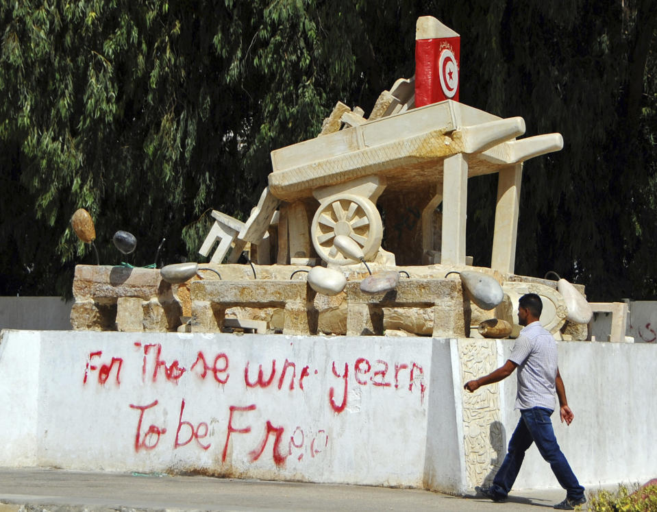 FILE - A Tunisian man walks past a graffiti reading 'for those who yearn to be free', during a general strike in the central Tunisian town of Sidi Bouzid, Tuesday, Aug. 14, 2012. To outsiders, Tunisia’s legislative elections Saturday, Dec. 17, 2022 look questionable: Many opposition parties are boycotting. A new electoral law makes it harder for women to compete. Foreign media aren’t allowed to talk to candidates. But many voters believe that their country’s decade-old democratic revolution has failed, and welcome their increasingly autocratic president’s political reforms. (AP Photo/Hassene Dridi, File)