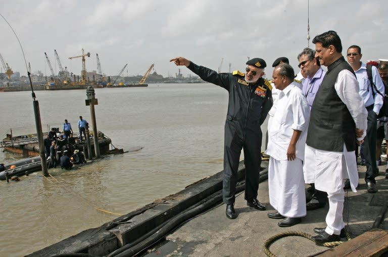 In this photo, released by the Ministry of Defence, Chief for Indian Naval Staff, Admiral D.K. Joshi (L), briefs Defence Minister A.K. Antony (C) at the scene of the stricken INS Sindhurakshak, after the submarine sank following an explosion at the naval dockyard, in Mumbai, on August 14, 2013. All 18 sailors on board of the submarine are feared dead