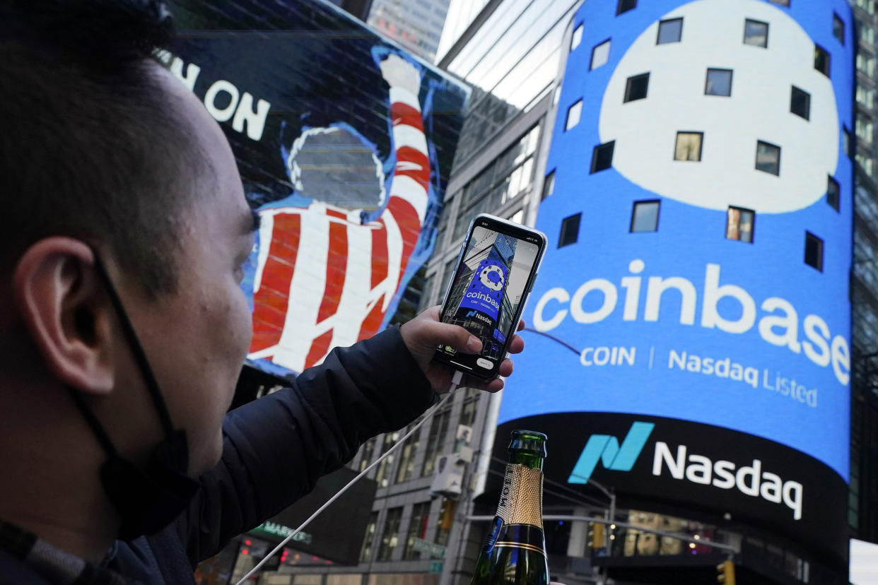 FILE - Coinbase employee Daniel Huynh holds a celebratory bottle of champagne as he photographs outside the Nasdaq MarketSite, in New York's Times Square, April 14, 2021. Coinbase rose, Friday, June 23, 2023, after winning a Supreme Court case. The crypto trading platform wanted to keep a dispute with a customer in arbitration, a process that many companies prefer over lawsuits in courts. (AP Photo/Richard Drew, File)