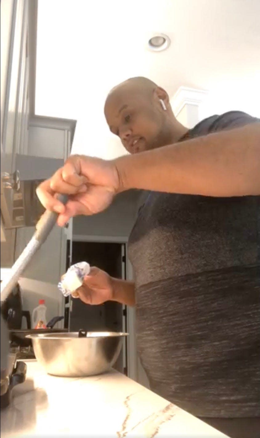 A man cooking at a stove stirring a pot.