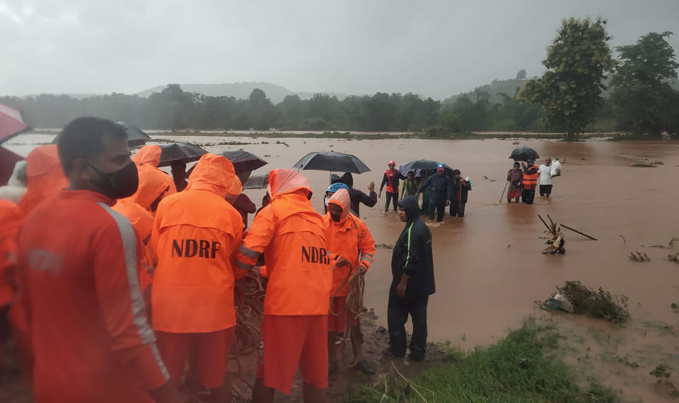 This photograph provided by India's National Disaster Response Force (NDRF) shows NDRF personnel rescuing people stranded in floodwaters in Chiplun, in the western Indian state of Maharashtra, Friday, July 23, 2021. Landslides triggered by heavy monsoon rains hit parts of western India, killing at least five people and leading to the overnight rescue of more than 1,000 other people trapped by floodwaters, an official said Friday. (National Disaster Response Force via AP)