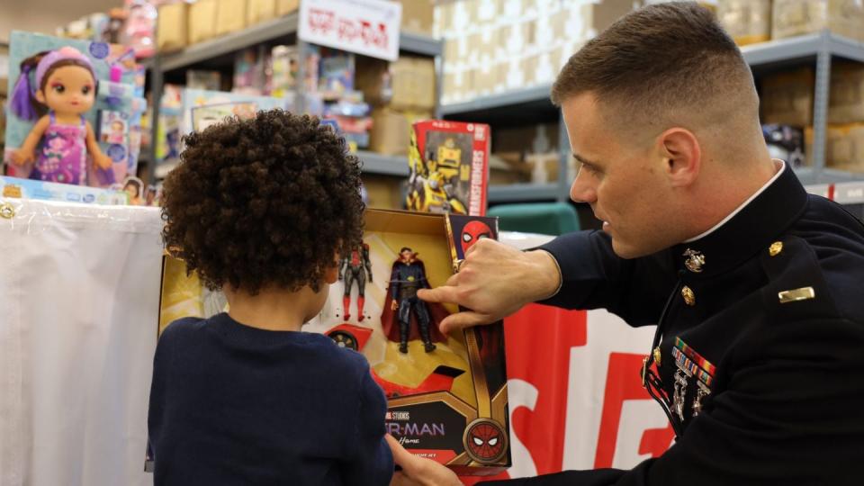 A Marine shows a child some of the toys available during a Toys for Tots event. (Courtesy Marine Toys for Tots Foundation)