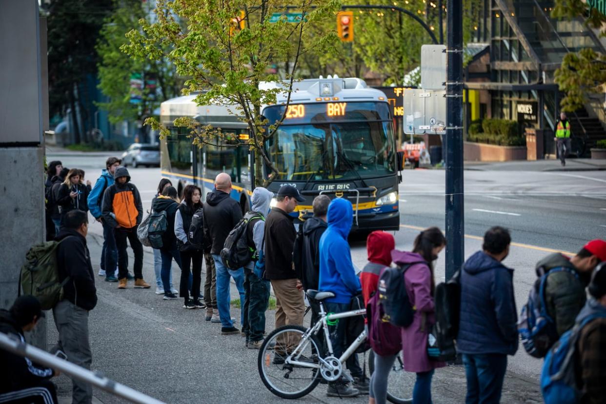 Commuters wait for the 250 bus, which is operated by Blue Bus, in April 2020. Unionized Blue Bus workers voted to ratify a collective agreement on Wednesday, averting the possibility of a strike.  (Ben Nelms/CBC - image credit)