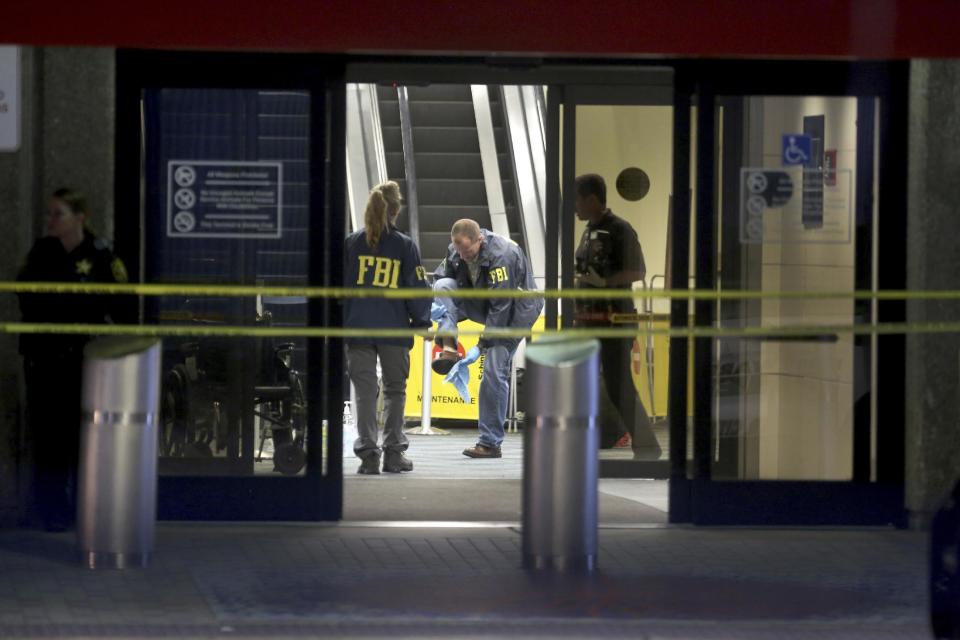 An FBI agent wipes off his shoe while working the crime scene in Terminal 2 at Ft. Lauderdale-Hollywood International Airport, Saturday, Jan. 7, 2017, the day after a shooting in the baggage area. Authorities say Army veteran Esteban Santiago of Anchorage, Alaska, drew a gun from his checked luggage on arrival and opened fire on fellow travelers. (Mike Stocker/South Florida Sun-Sentinel via AP)