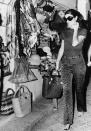 <p>Jackie, while shopping on holiday in southern Italy, wears patterned pants, chic leather sandals, and a draped belt. Oversize sunglasses, hoop earrings, and sandals complete the casual look.<br></p>