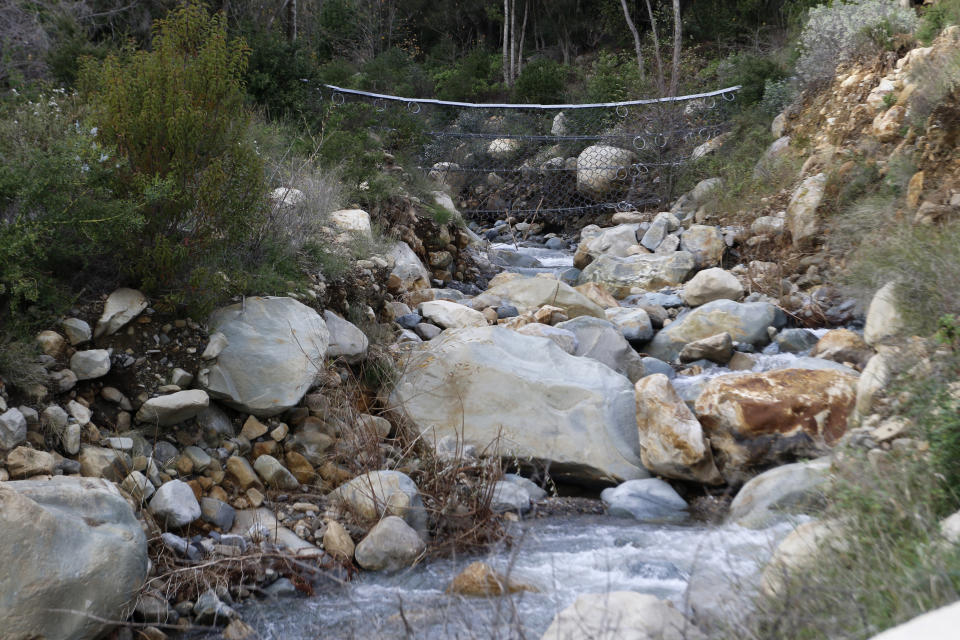Netting made from mettle cables is visible above a creek in Montecito, Calif., on Thursday, Jan. 12, 2023. With climate change predicted to produce more severe weather, officials are scrambling to put in basins, nets and improve predictions of where landslides might occur to keep homes and people safe. (AP Photo/Ty O'Neil)