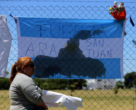 A woman sits next to a banner in support of the 44 crew members of the missing at sea ARA San Juan submarine, outside an Argentine naval base in Mar del Plata, Argentina November 25, 2017. The banner reads "ARA San Juan, be strong". REUTERS/Marcos Brindicci