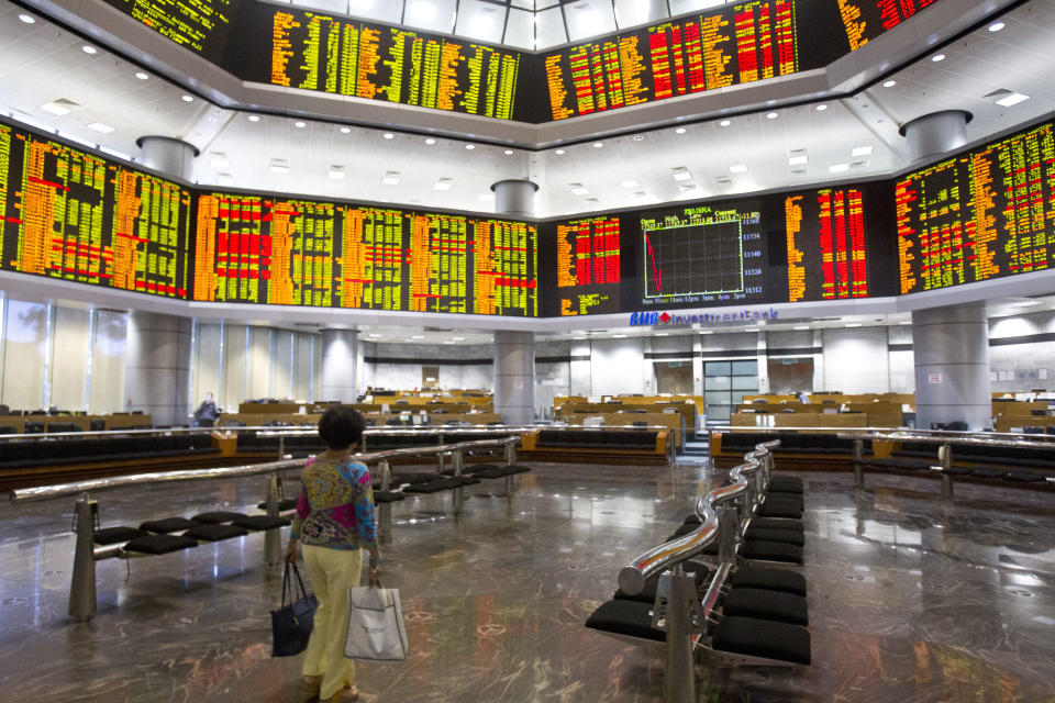 An investor walks in front of private stock trading boards at a private stock market gallery in Kuala Lumpur, Malaysia, Monday, Oct. 29, 2018. Asian stock prices were mixed Monday after Wall Street extended its slide, fueling concern about the global market outlook. (AP Photo/Yam G-Jun)