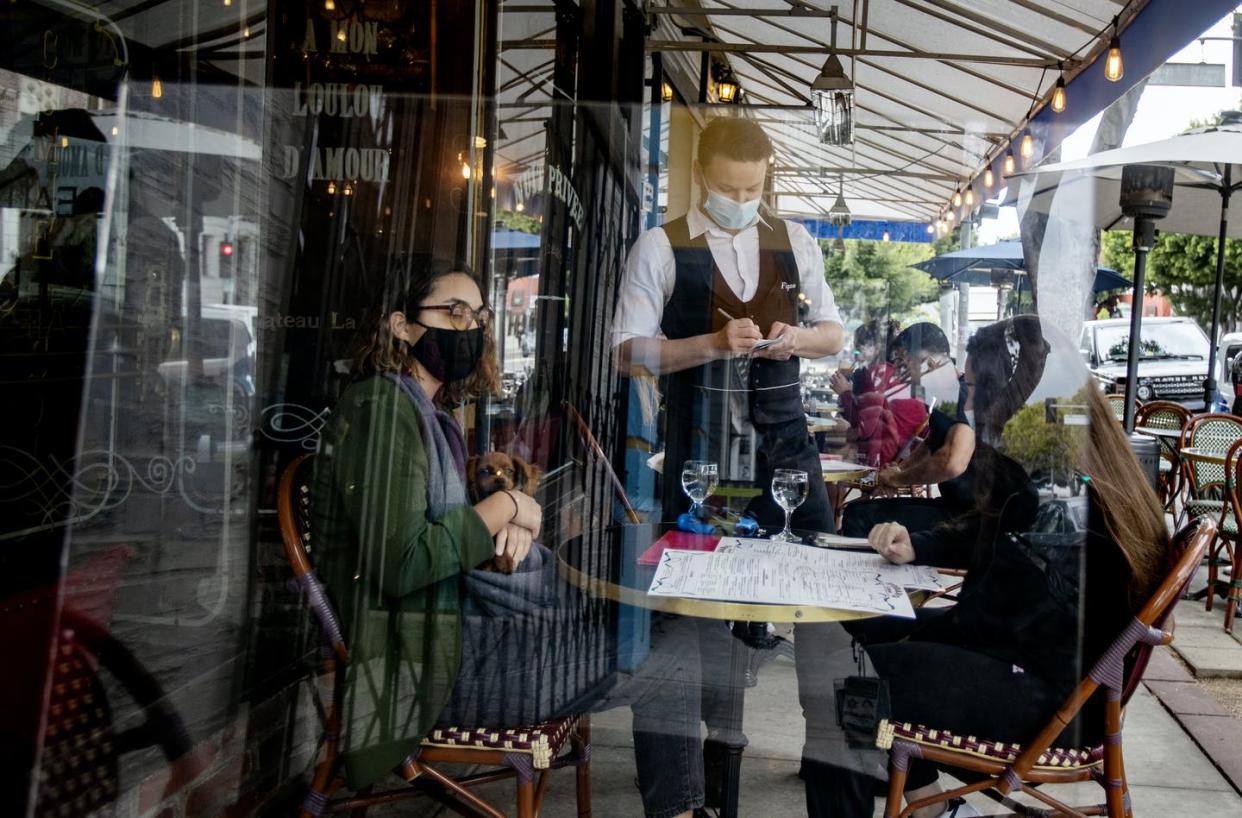 <span class="caption">The dining-out experience has changed as people wear masks and are separated by plexiglass in outdoor dining.</span> <span class="attribution"><a class="link " href="https://www.gettyimages.com/detail/news-photo/waiter-boris-macquin-serves-customers-behind-plexiglass-news-photo/1231905438?adppopup=true" rel="nofollow noopener" target="_blank" data-ylk="slk:Gina Ferazzi / Los Angeles Times via Getty Images;elm:context_link;itc:0;sec:content-canvas">Gina Ferazzi / Los Angeles Times via Getty Images</a></span>