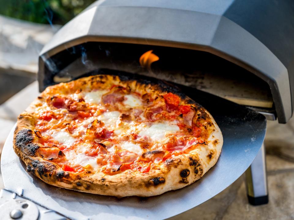 Pizza on a pizza steel being taken out of an oven