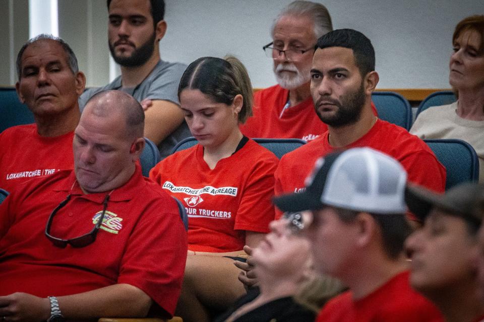 Ricardo Alonzo, right, sits with his wife Natalia Melian during public comments at the Palm Beach County Commission meeting in downtown West Palm Beach, Fla. on January 25, 2024. The couple joined other red shirt-wearing citizens who attended the meeting.