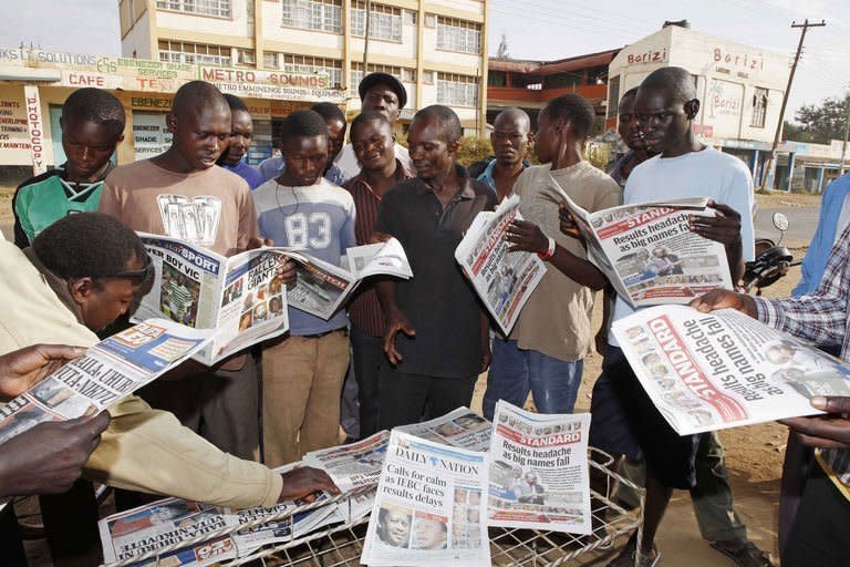 People gather around a newspaper stand on March 6, 2013 in Kisumu