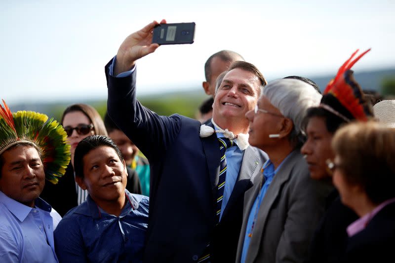 Brazil's President Jair Bolsonaro poses for picture with Brazilian Indians from different ethnic groups before a national flag hoisting ceremony in front the Alvorada Palace in Brasilia