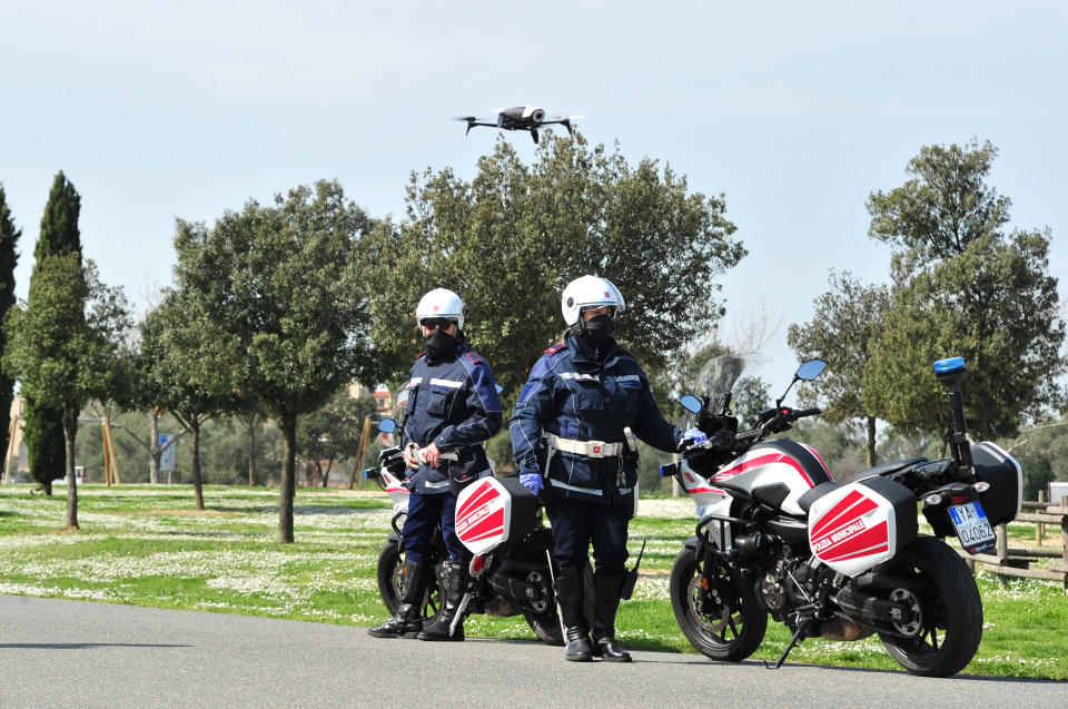 City police officers with the help of a drone monitor citizens' movements in Grosseto, central Italy, Friday, March 20, 2020 as mayors of many towns in Italy are asking for ever more stringent measures on citizens’ movements to help contain the surging infections of the coronavirus. Despite a national lockdown, strictly limiting the justified reasons why they can leave their homes, there have been many violators. For most people, the new coronavirus causes only mild or moderate symptoms. For some it can cause more severe illness.(Jennifer Lorenzini/LaPresse via AP)