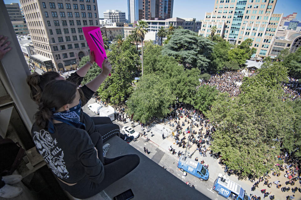 Protesters sit in on top of a parking garage near Cesar Chavez Plaza in Sacramento, Calif., Saturday, June 6, 2020, looking over a large crowd gathered to protest the killing of George Floyd that had marched from Golden 1 Center. The protest is sparked by the death of George Floyd, who died May 25 after he was restrained by Minneapolis police. (Jason Pierce/The Sacramento Bee via AP)