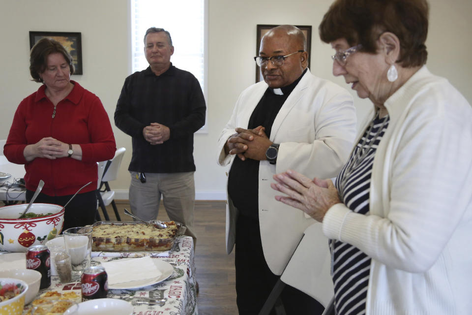 Michele and Frank Varisco, left, pray with the Rev. Athanasius Abanulo and Evelyn Smith, right, before eating lunch at Immaculate Conception Catholic Church in Wedowee, Ala., on Sunday, Dec. 12, 2021. (AP Photo/Jessie Wardarski)