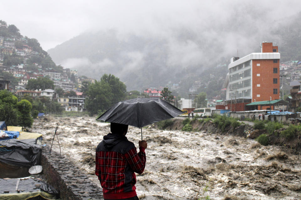 A man looks at a swollen River Beas following heavy rains in Kullu, Himachal Pradesh, India, Sunday, July 9, 2023. According to local reports heavy rain fall has triggered landslides, damaged houses and caused loss of lives. (AP Photo/ Aqil Khan)