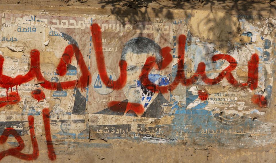 Graffiti reading "I love you," covers defaced campaign posters for ousted President Mohammed Morsi in Cairo, Egypt, Wednesday, Jan. 8, 2014. The judge in the trial of Egypt's former Islamist president on charges of inciting murder has ordered the hearings adjourned until Feb. 1 after bad weather prevented bringing Morsi to court. (AP Photo/Amr Nabil)