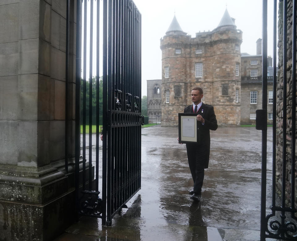 A member of royal household staff posts a notice on the gates of the Palace of Holyroodhouse in Edinburgh announcing the death of Queen Elizabeth II. Picture date: Thursday September 8, 2022. (Photo by Jane Barlow/PA Images via Getty Images)