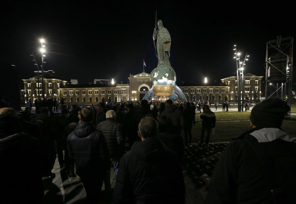 People walk around a 23-meter-high, 70-ton bronze sculpture of the legendary founder of the Serbian state, Stefan Nemanja, during the unveiling ceremony in Belgrade, Serbia, Wednesday, Jan. 27, 2021. President Aleksandar Vucic's allies say the bronze sculpture of Stefan Nemanja will be a new landmark of the Serbian capital. Opponents think the monument is a megalomaniac and pricy token of Vucic's populist and autocratic rule that should be removed. (AP Photo/Darko Vojinovic)