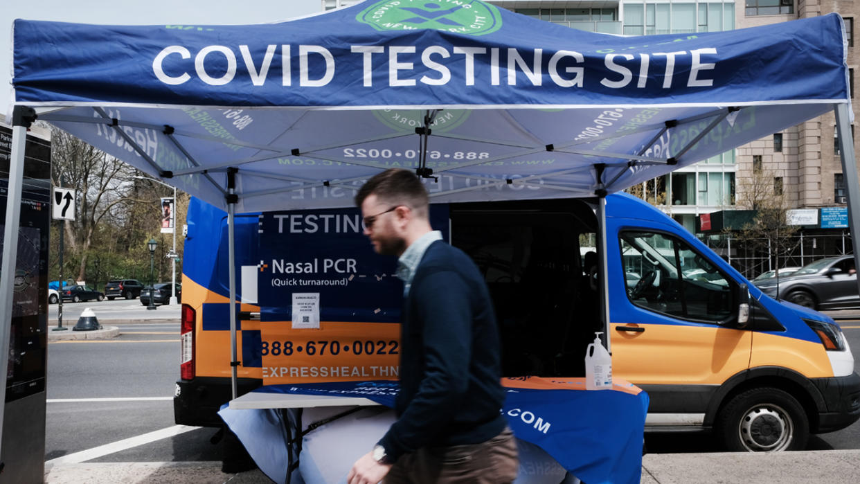 A person walks by a pop-up tent labeled: COVID Testing Site.