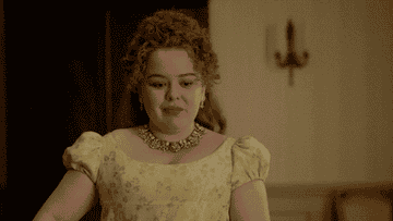 Nicola Coughlan dressed in Regency-style attire, wearing a yellow dress with puffed sleeves and a jeweled necklace