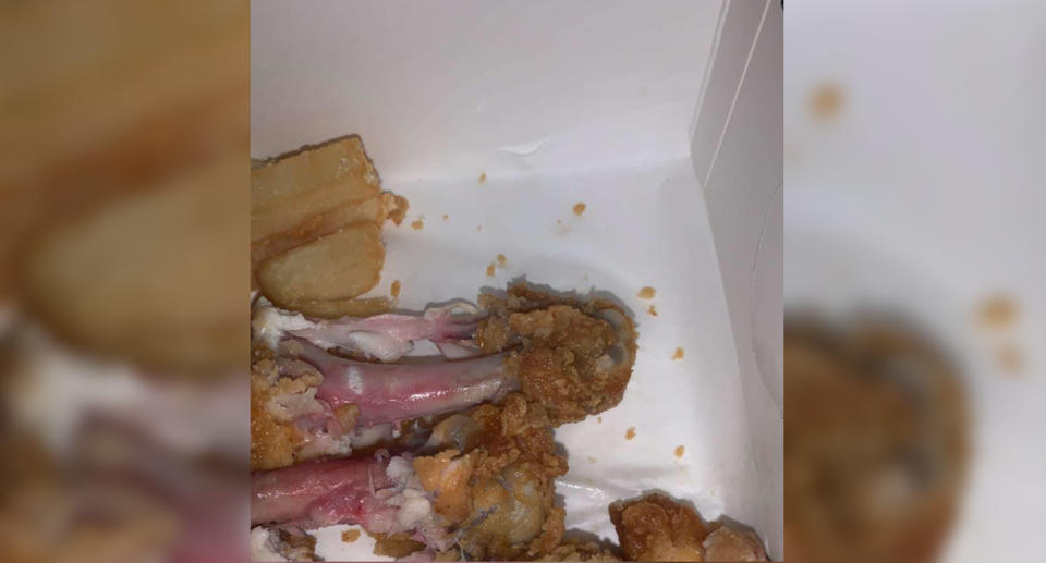 The KFC chicken can be seen inside its takeaway packaging beside fries, with the chicken appearing pink and raw.