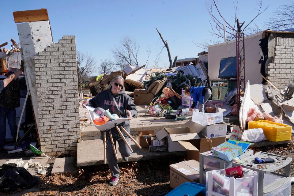 Belinda Penner carries belongings from her cousin's home, destroyed by a tornado on Tuesday in Wayne, Okla.