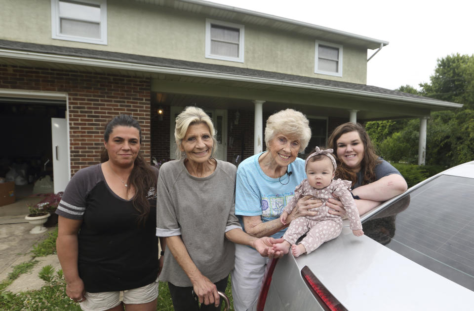 Tressie Corsi, center, poses with her granddaughter Tiffany Hollis, left, Corsi's daughter Denise Kelly, Corsi's great great granddaughter Amelia Hollis and Corsi's great granddaughter Allie Hollis outside of the house she has owned in Johnstown, Ohio, since 1972 that she is giving up to make way for an Intel manufacturing plant during an interview Monday, June 20, 2022. (AP Photo/Paul Vernon)