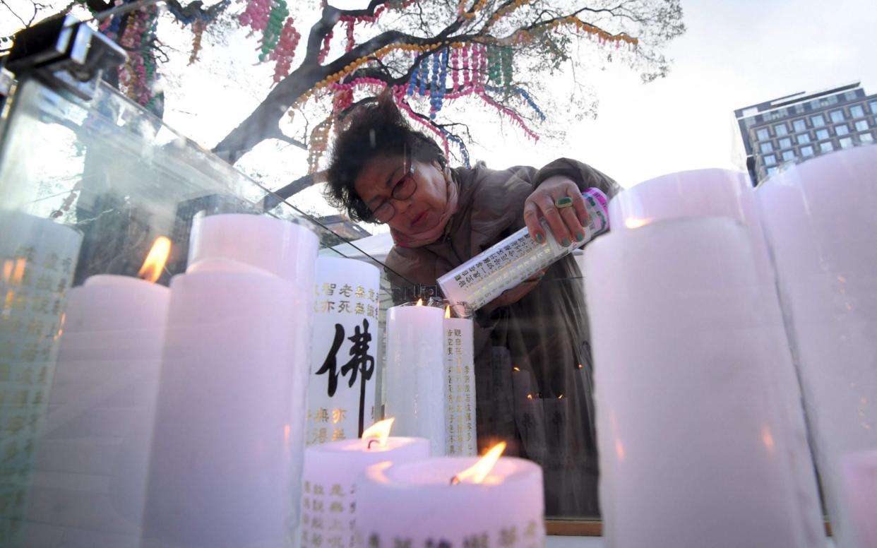 A woman lights and places a candle for the success of her relative sitting the annual College Scholastic Ability Test  - AFP