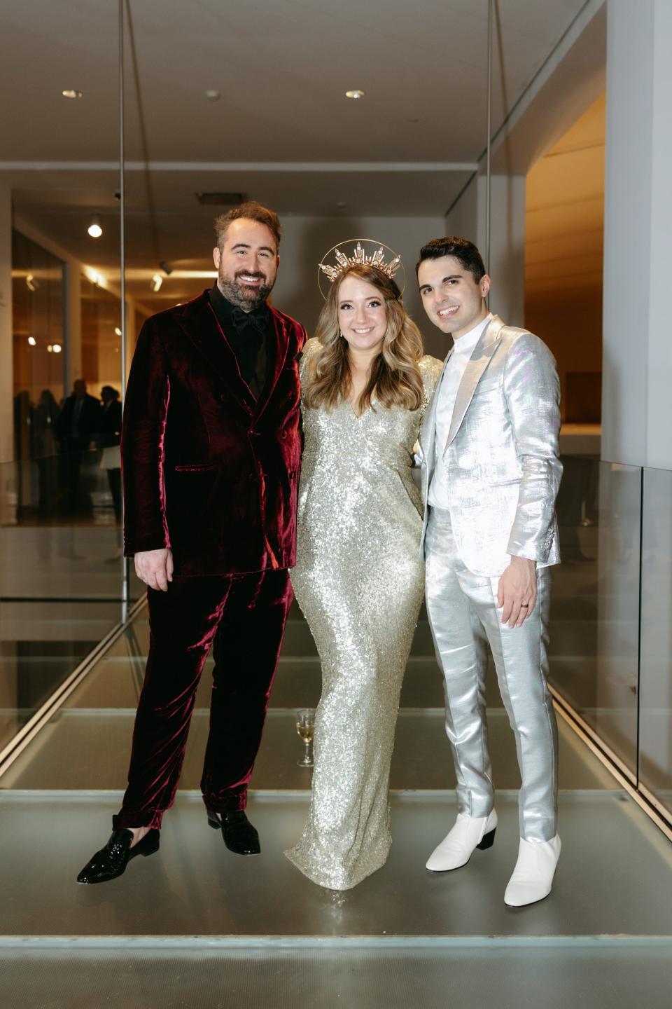 Three people in colorful outfits stand together.
