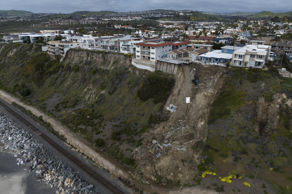 In this image taken with a drone, a mass of debris is seen along a cliff beneath residential homes after a landslide occurred in San Clemente, Calif., Thursday, March 16, 2023. (AP Photo/Jae C. Hong)