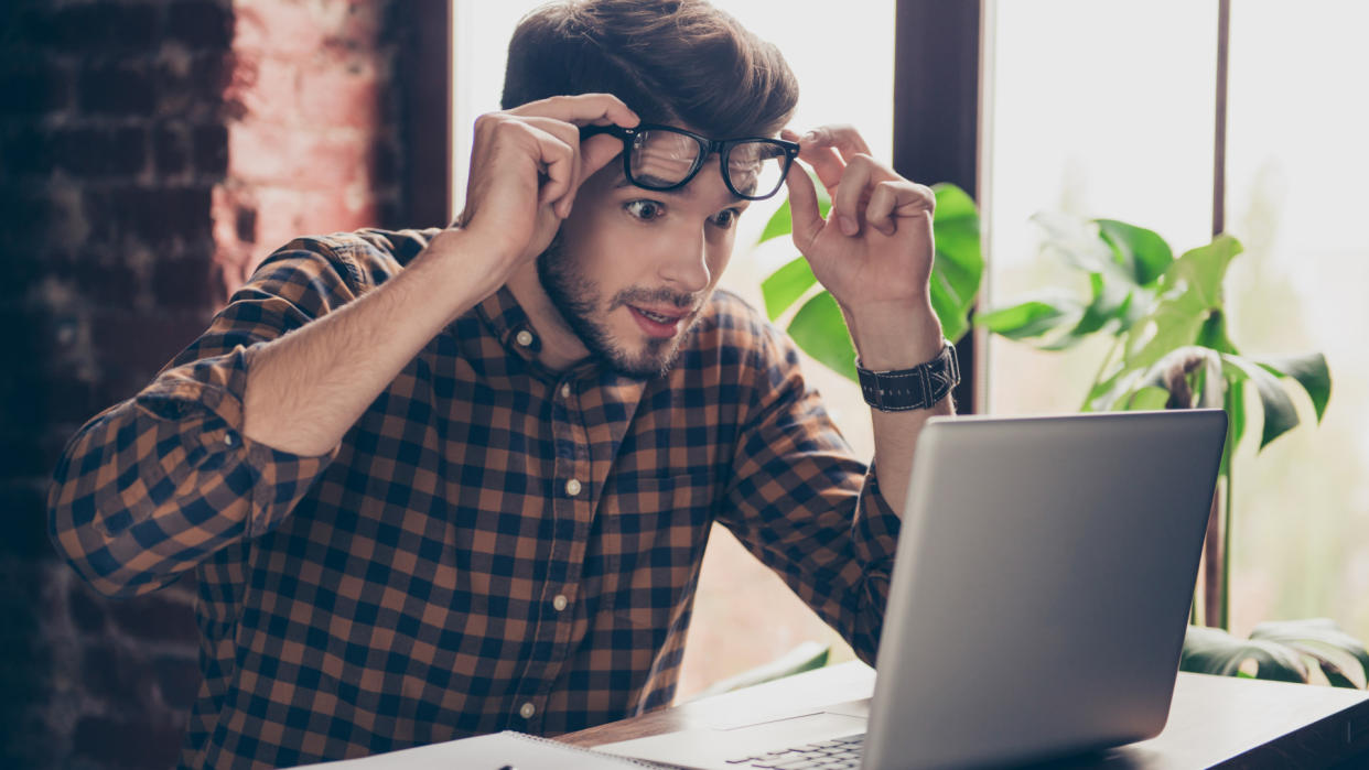  A young person looking very surprised at their laptop 