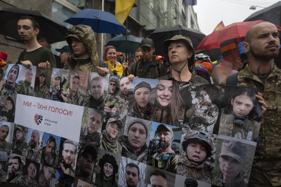 Soldiers hold portraits of LGBT Ukrainian servicemen, who are fighting on the frontline, with the poster reading, "We are their voices," in Kyiv, Ukraine, Sunday, June 16, 2024. Several hundred LGBT Ukrainian servicemen and other protesters joined the pride march in central Kyiv Sunday seeking legal reforms to allow people in same-sex partnerships to take medical decisions for wounded soldiers and bury victims of the war with Russia that extended across Ukraine more than two years ago. (AP Photo/Efrem Lukatsky)