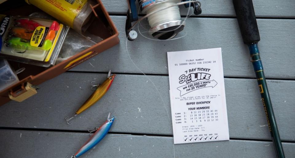 A Set for Life ticket sits on ground beside fishing gear. 