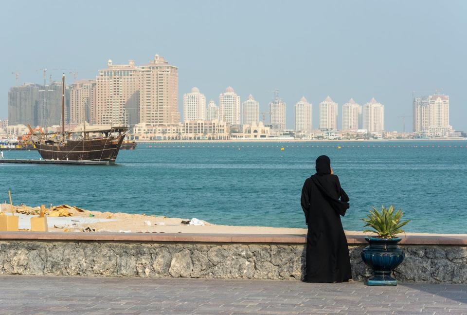 Una mujer observa los rascacielos de Doha, la capital de Catar. <a href="https://www.shutterstock.com/es/image-photo/street-scene-doha-qatar-lady-wearing-1274477314" rel="nofollow noopener" target="_blank" data-ylk="slk:Shutterstock / Alizada Studios;elm:context_link;itc:0;sec:content-canvas" class="link ">Shutterstock / Alizada Studios</a>