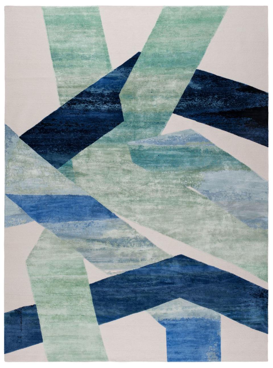 geometric rug in slashes of blue and light greens on a pale ecru background