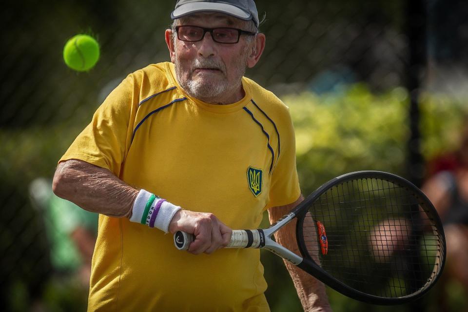 Ukrainian refugee Leonid Stanislavskyi hits a backhand Monday during men's singles in the over-90 division against George McCabe of Oxford, Ohio at the ITF Super Seniors World Tennis Championships at Coral Lakes Tennis Center in Boynton Beach.