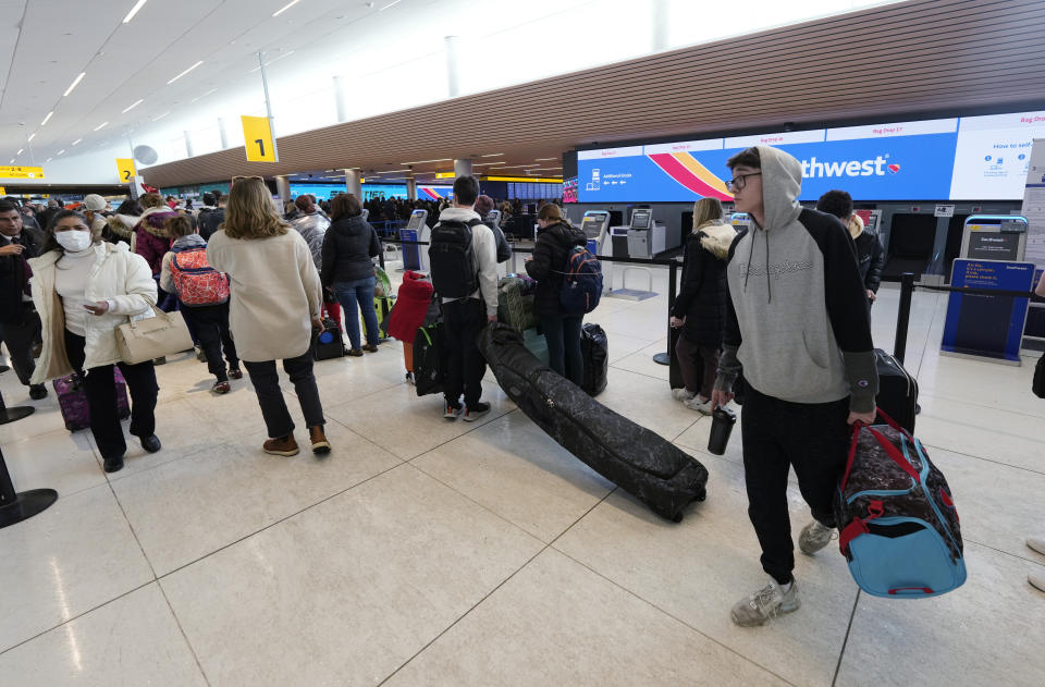 Travelers queue up to reach the check-in counters for Southwest Airlines in Denver International Airport after a winter storm swept over the country packing snow combined with Arctic cold, which created chaos for people trying to reach their destinations before the Christmas holiday, Friday, Dec. 23, 2022, in Denver. Forecasters predict that warmer weather will be on tap for the week ahead. (AP Photo/David Zalubowski)