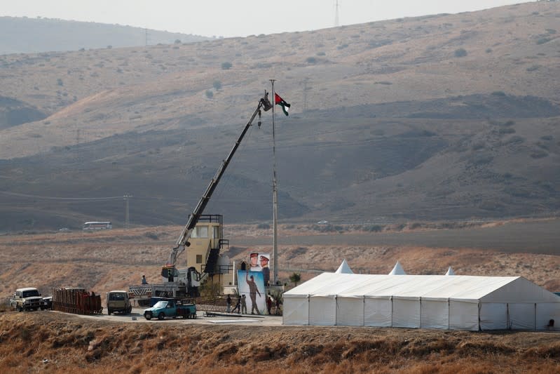 Jordanian soldiers lower a Jordanian national flag near a tent at the "Island of Peace" in an area known as Naharayim in Hebrew and Baquora in Arabic, on the Jordanian side of the border with Israel, as seen from the Israeli side