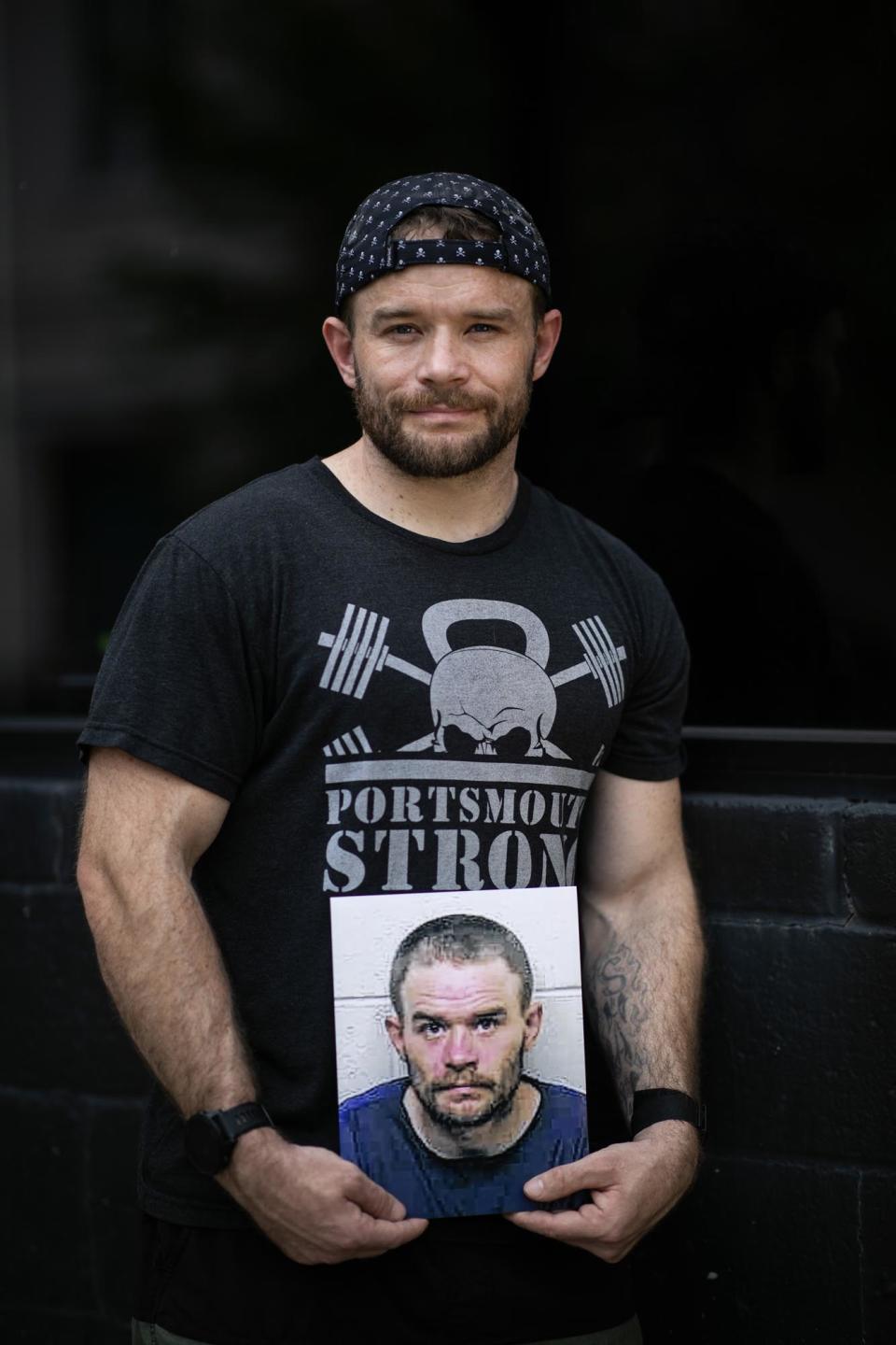 Ricky Shaw holds his old mug shot in front of PSKC CrossFit, where he is now a trainer, in Portsmouth, OH on May 8, 2023.