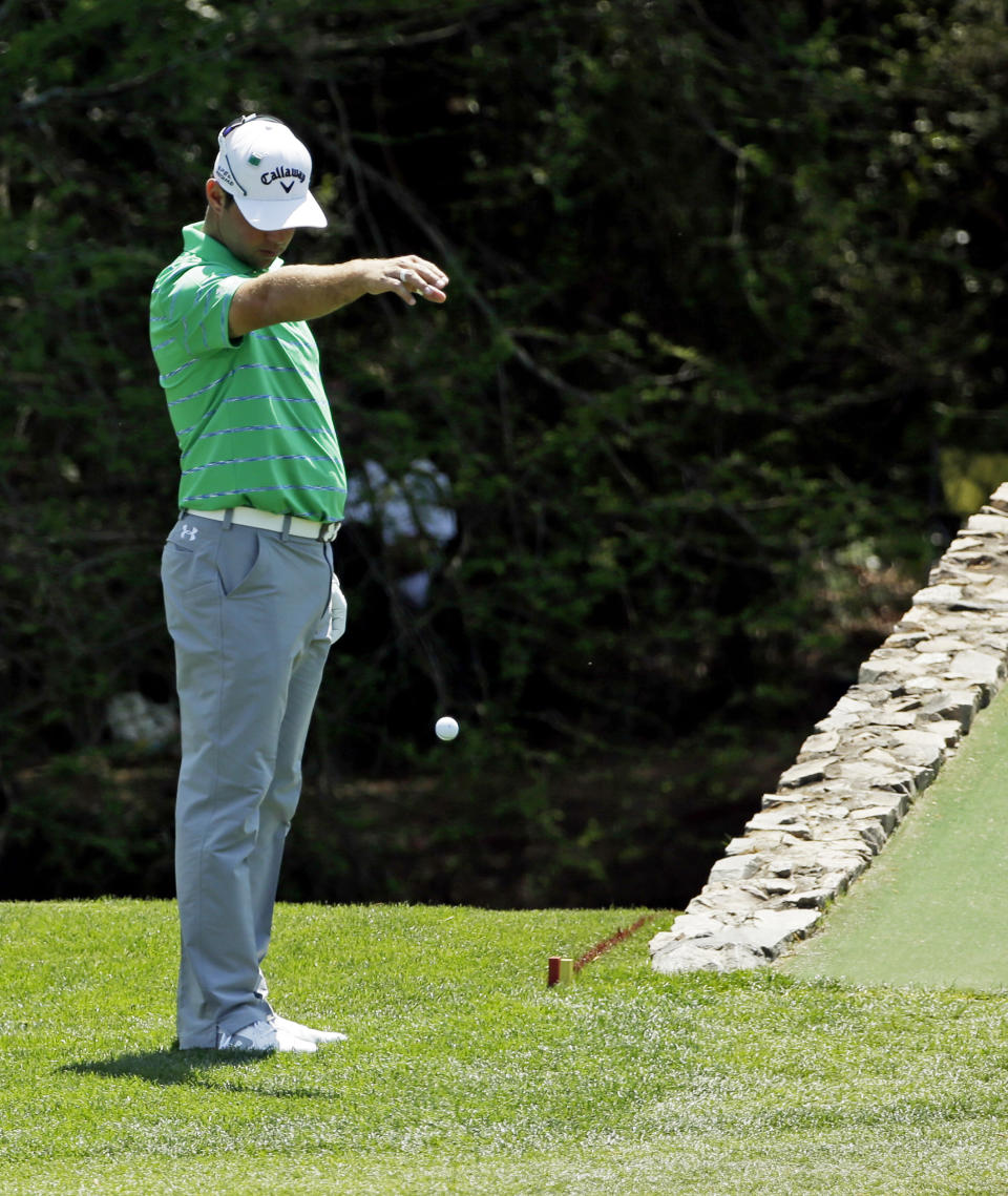 Gary Woodland takes a ball drop after his tee shot from the 12th hole landed in the water during the third round of the Masters golf tournament Saturday, April 12, 2014, in Augusta, Ga. (AP Photo/David J. Phillip)