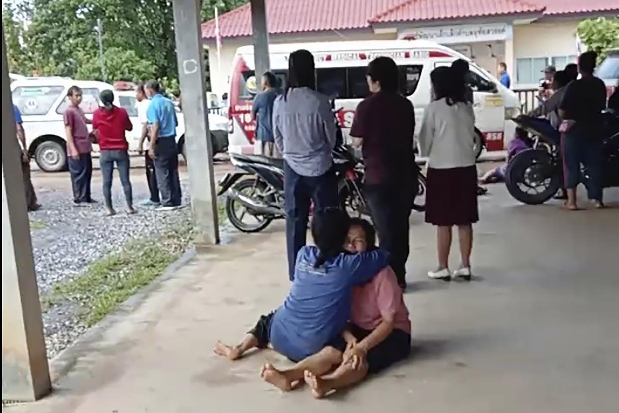In this image taken from video, a distraught woman is comforted outside the site of an attack at a daycare center, Thursday, Oct. 6, 2022, in the town of Nongbua Lamphu, northeastern Thailand.