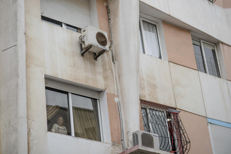 In this Tuesday, July 16, 2019 photo, Fatimazehra El Ghazaoui, 27, a woman affected by a rare disorder called xeroderma pigmentosum, or XP, stands at the window of her home, in Mohammedia, near Casablanca, Morocco. (AP Photo/Mosa'ab Elshamy)