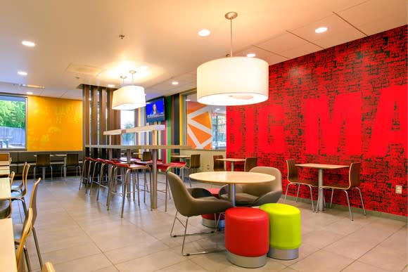 Interior view of a remodeled McDonald's with modern lamps hanging from the ceiling, modern seating, and a flat-screen TV on the wall.