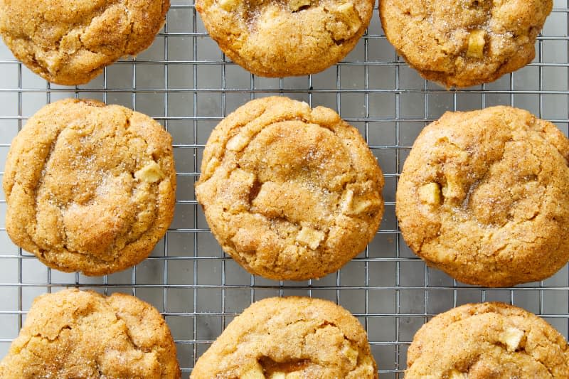 Caramel apple cookies cooling on a silver baking rack on a marble surface.