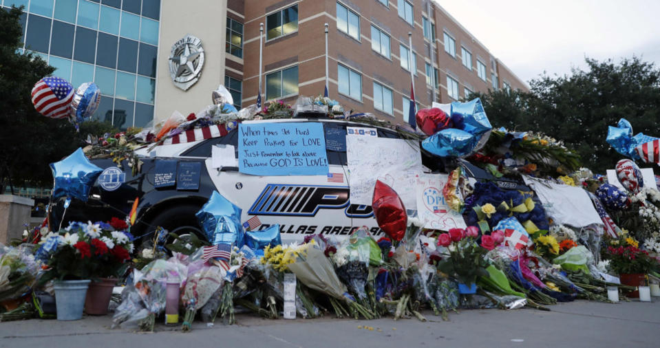 Two Dallas police patrol cars are covered with notes, flowers, balloons and other items as part of a makeshift memorial